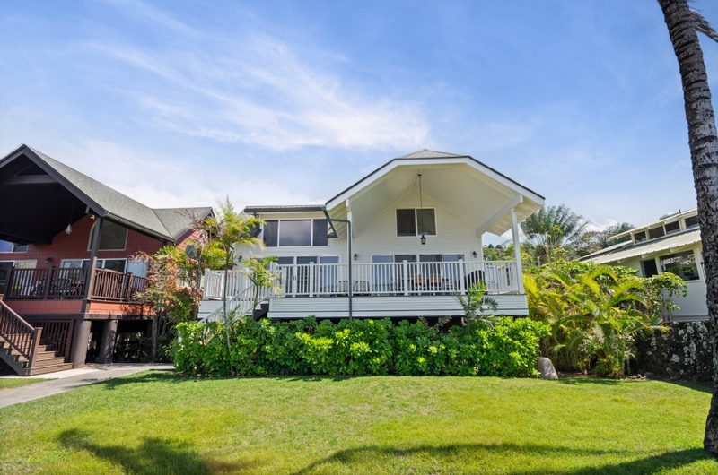 Hibiscus House, a white beach house with a long deck and a lawn running down to the sand