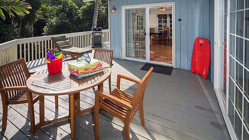 The deck at Plumeria House, with a table, beach towels and a boogie board by the door